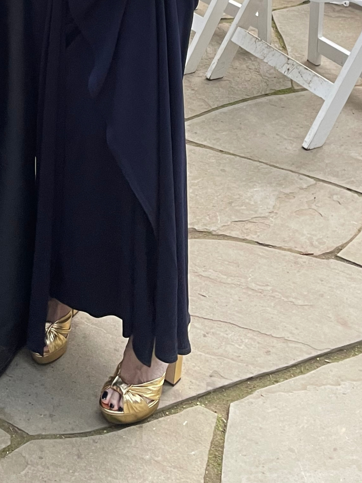 Close up of woman wearing long navy gown and gold Jimmy Choo platform sandals.