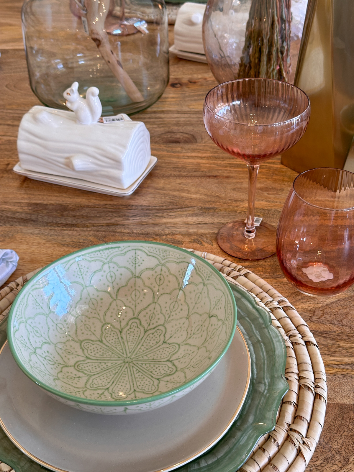 Green bowl on top of table setting and pink wine glasses.