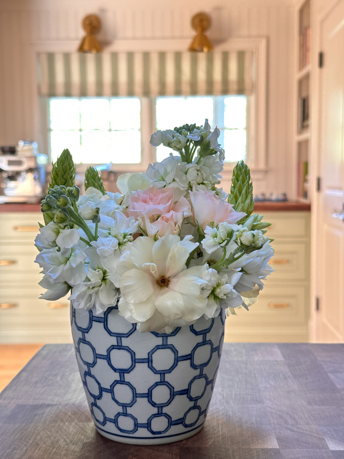 Blue and white planter filled with white and pink flowers sitting on a kitchen island.
