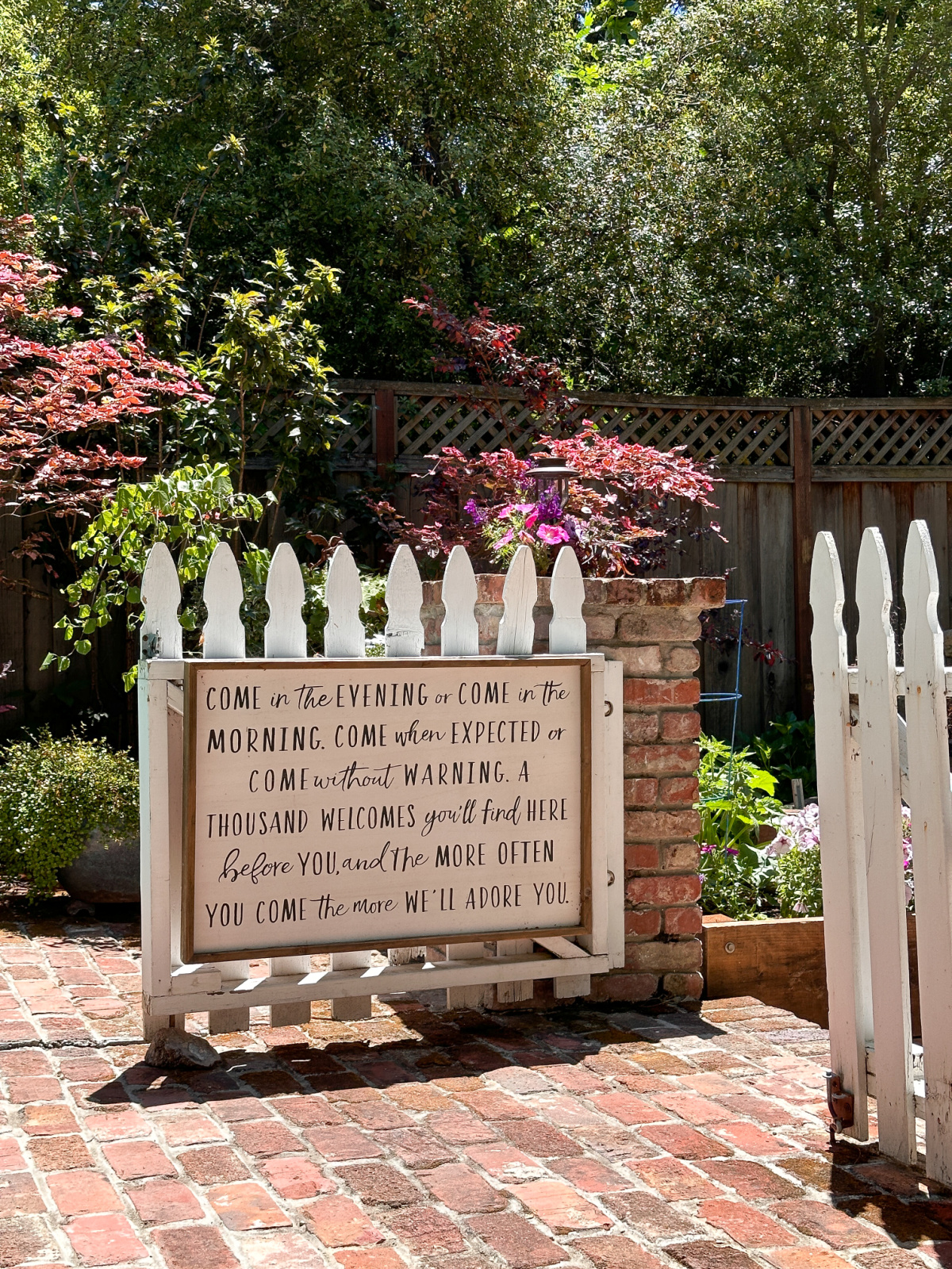 White picket garden gate at entrance to raised bed kitchen garden, with sweet poem.