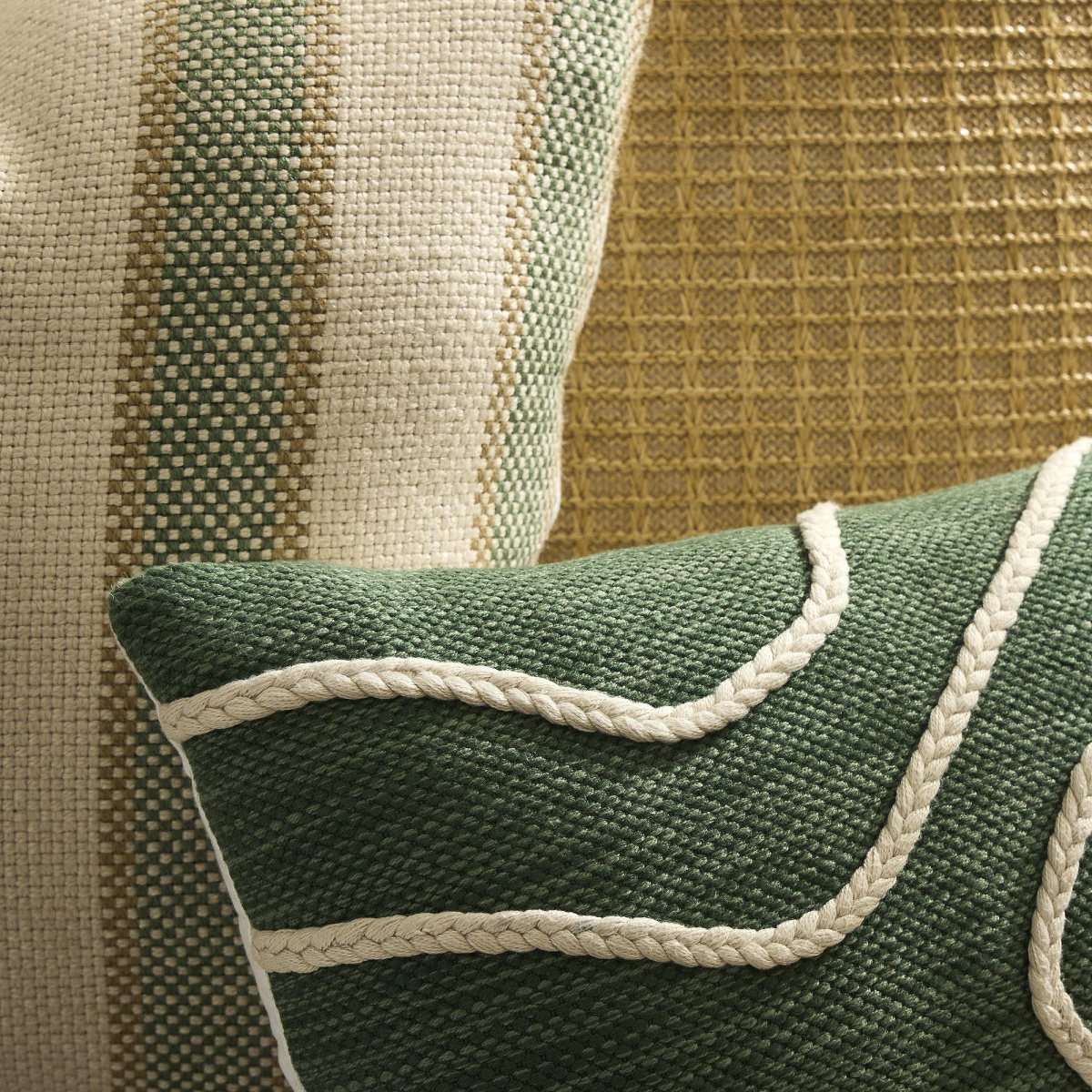Close up of three outdoor pillows in greens and naturals.