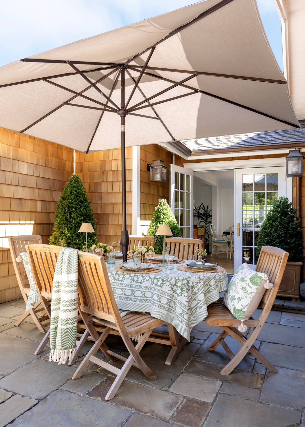 Outdoor patio table setting with umbrella overhead.