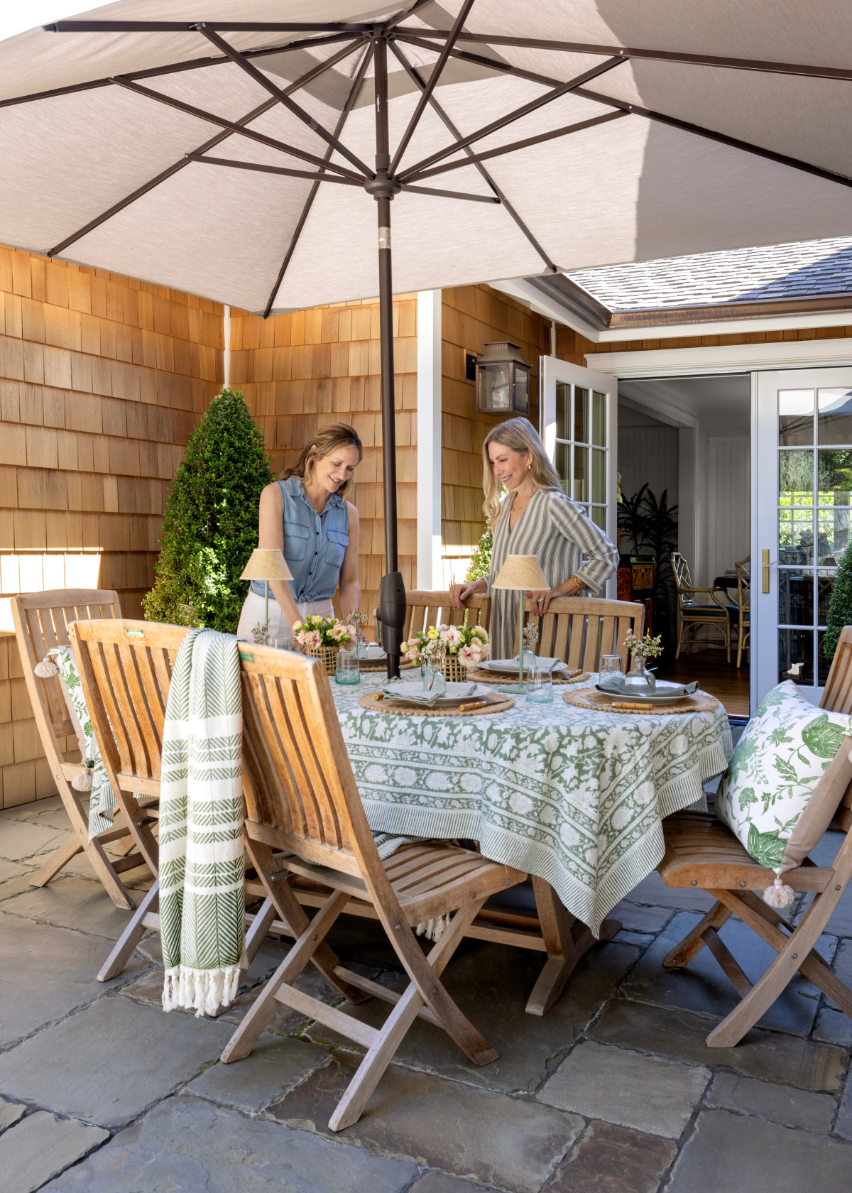 Two women standing behind pretty outdoor table set for summer.