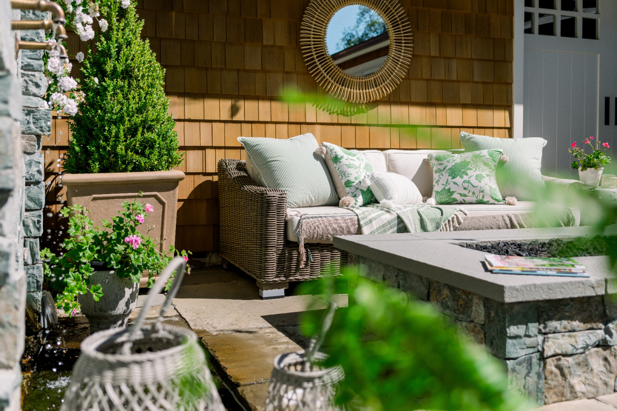 Outdoor patios with wicker sofas and green and white pillows.