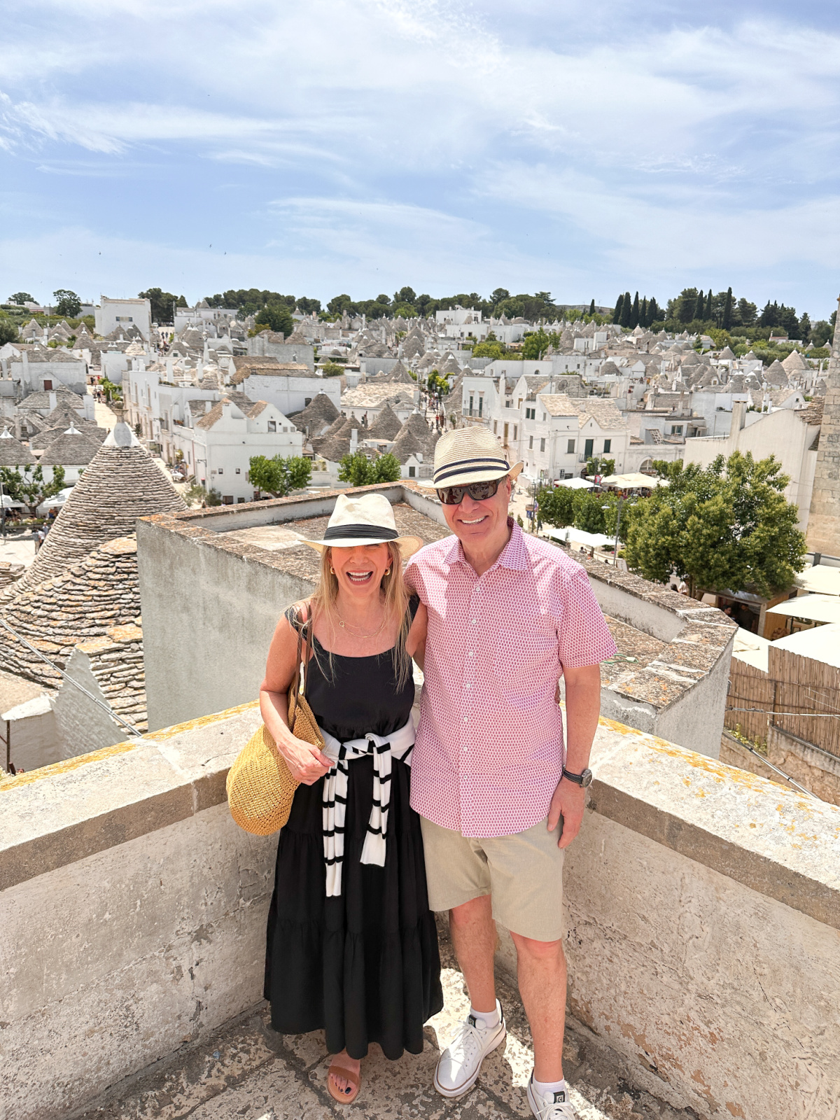Couple standing in front of the backdrop of Alberobello, Italy.