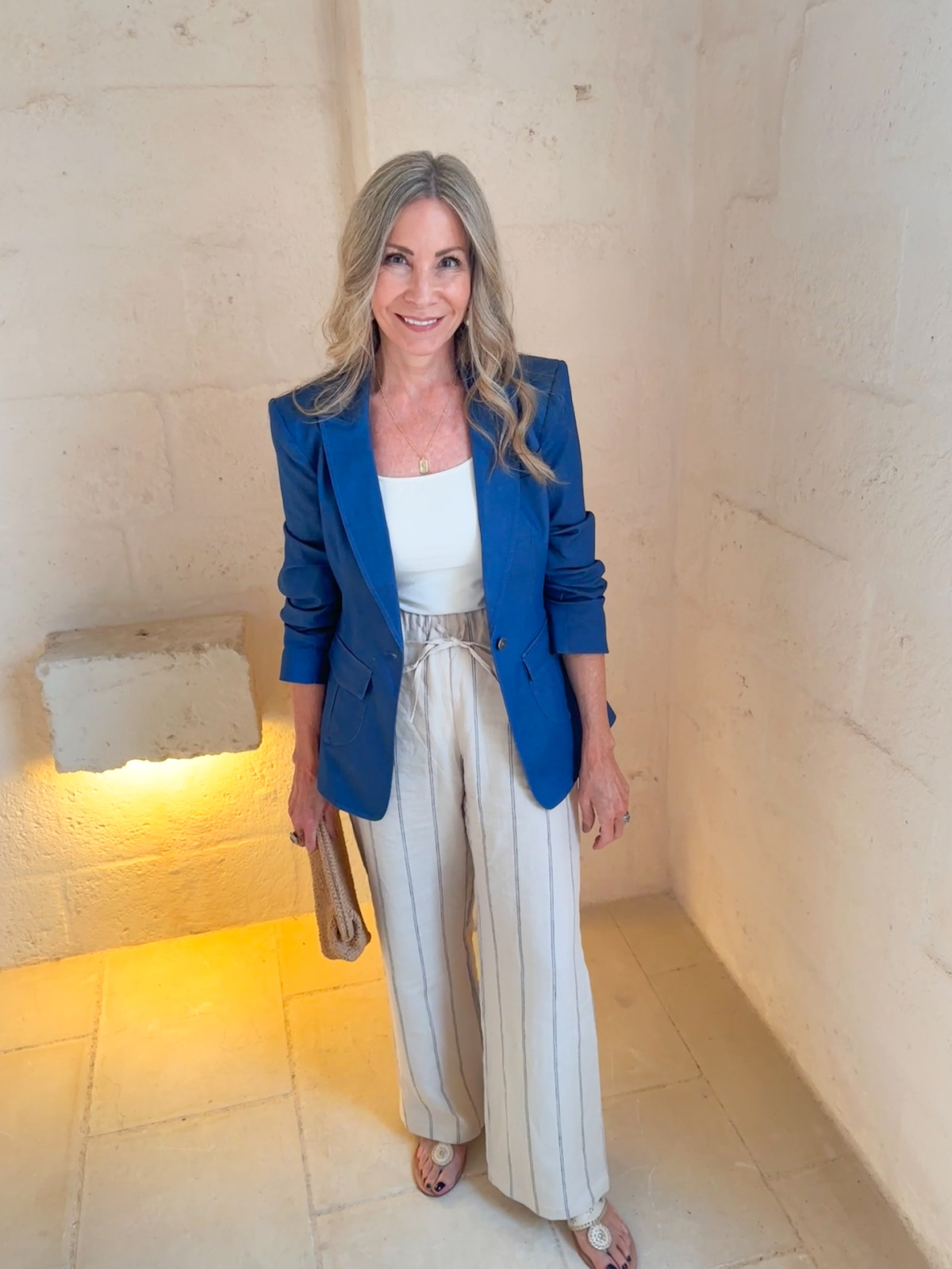 Woman wearing linen pants, camisole and blue blazer in hotel lobby.