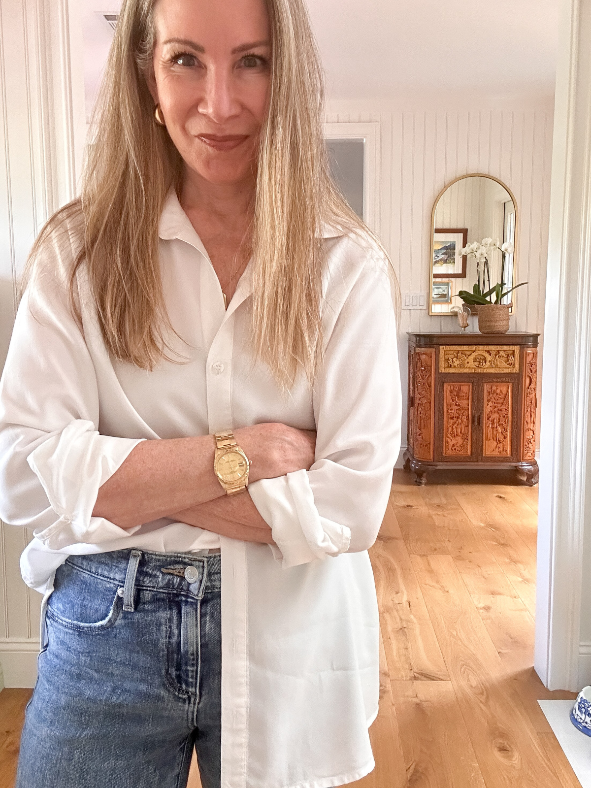 Woman wearing oversized white shirt and jeans.