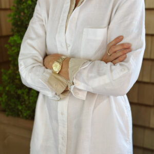 Woman wearing layered shirt dresses with arms crossed.